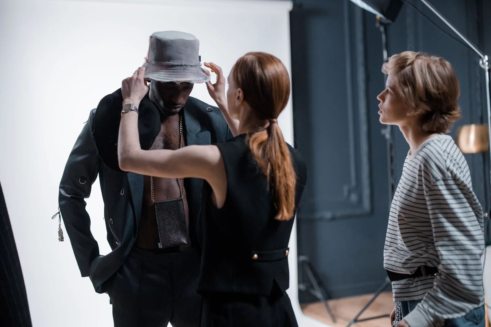 Stylist adjusting a model's jacket during a studio shoot