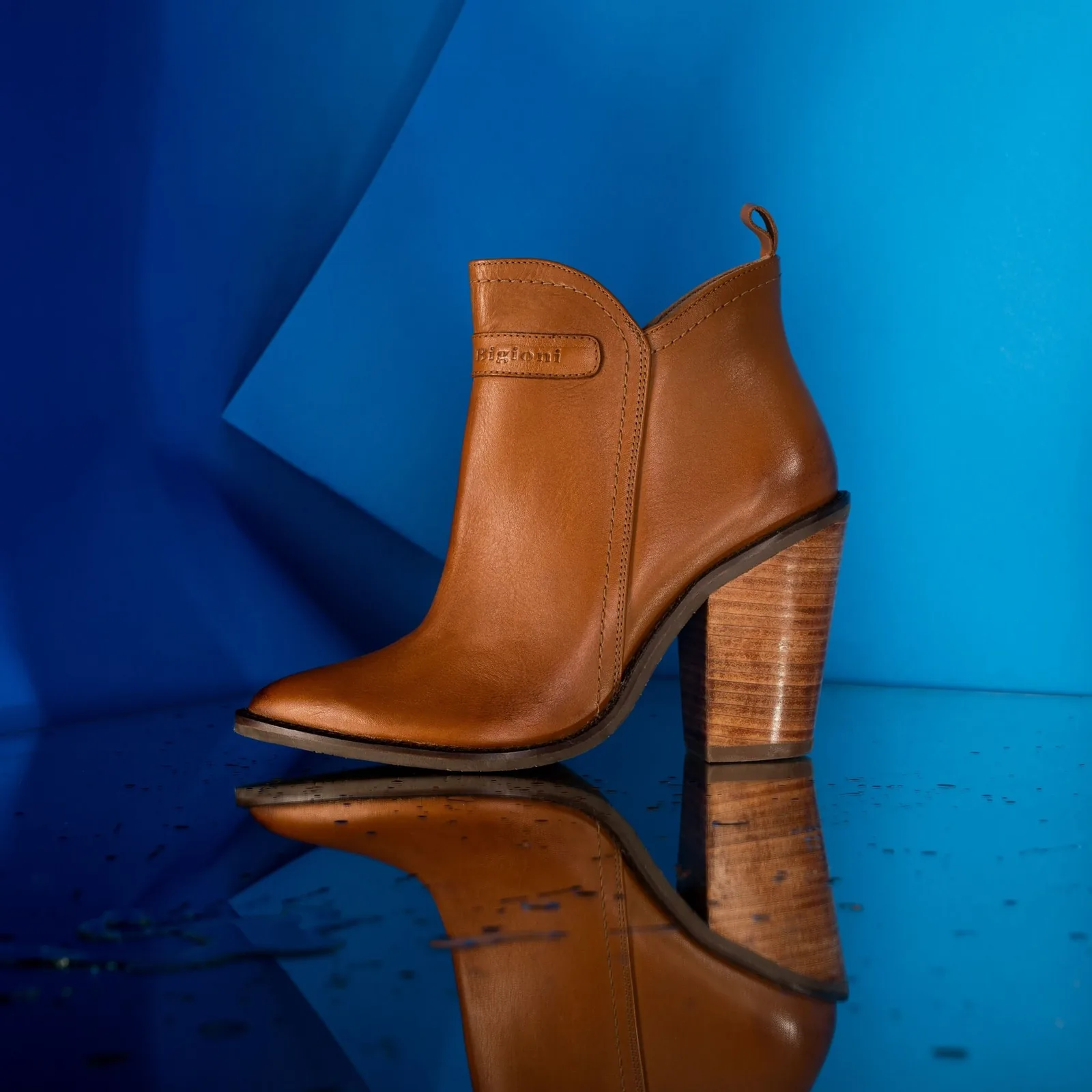 Packshot: tan leather ankle boot on blue