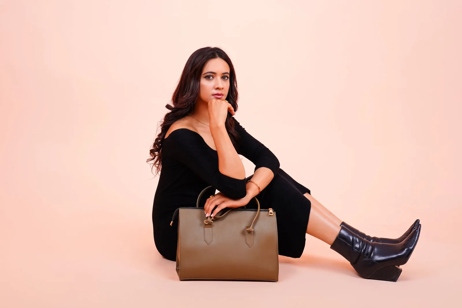 Model seated with a tan bag beside her