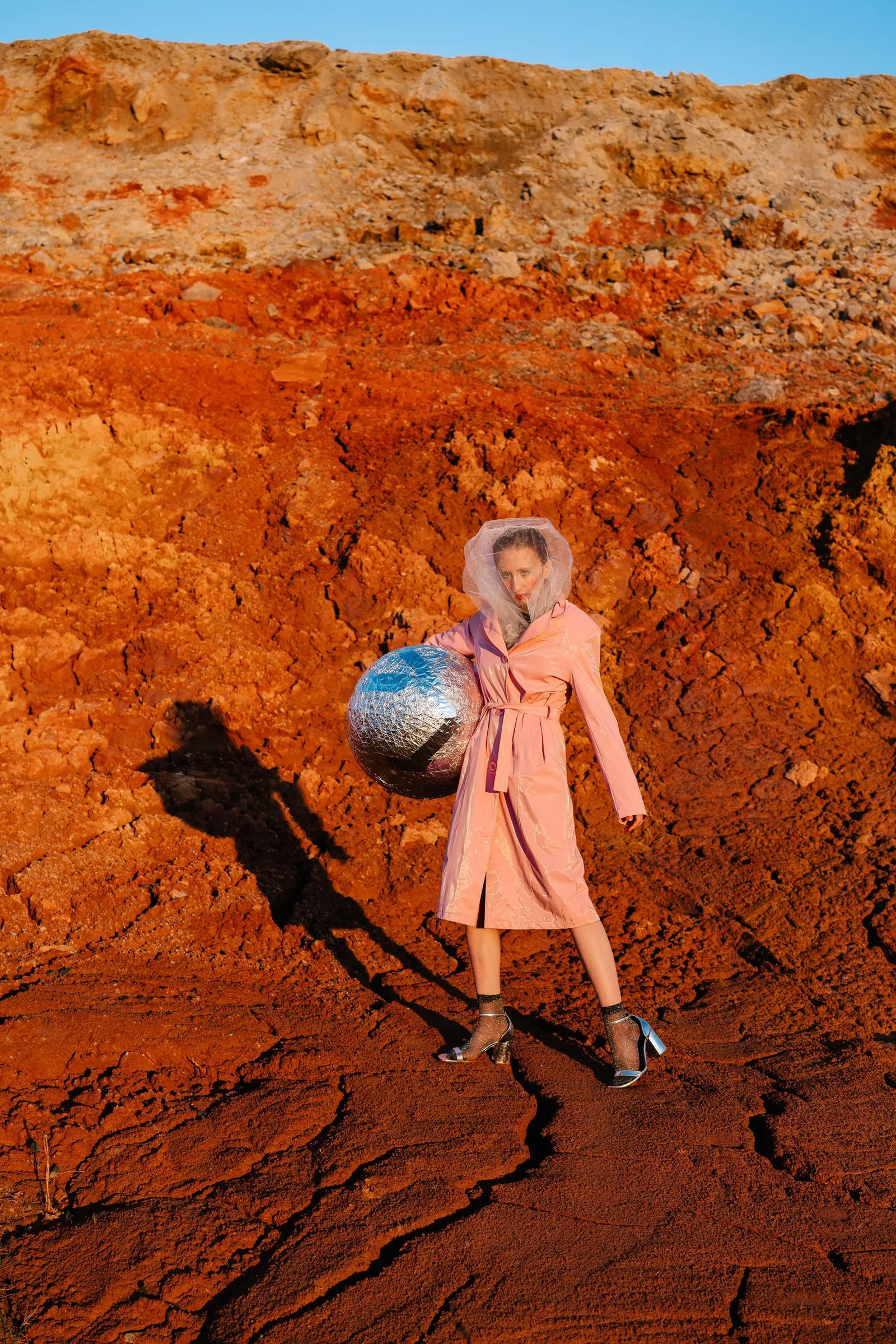 Campaign: model in a pink coat holding a mirror ball
