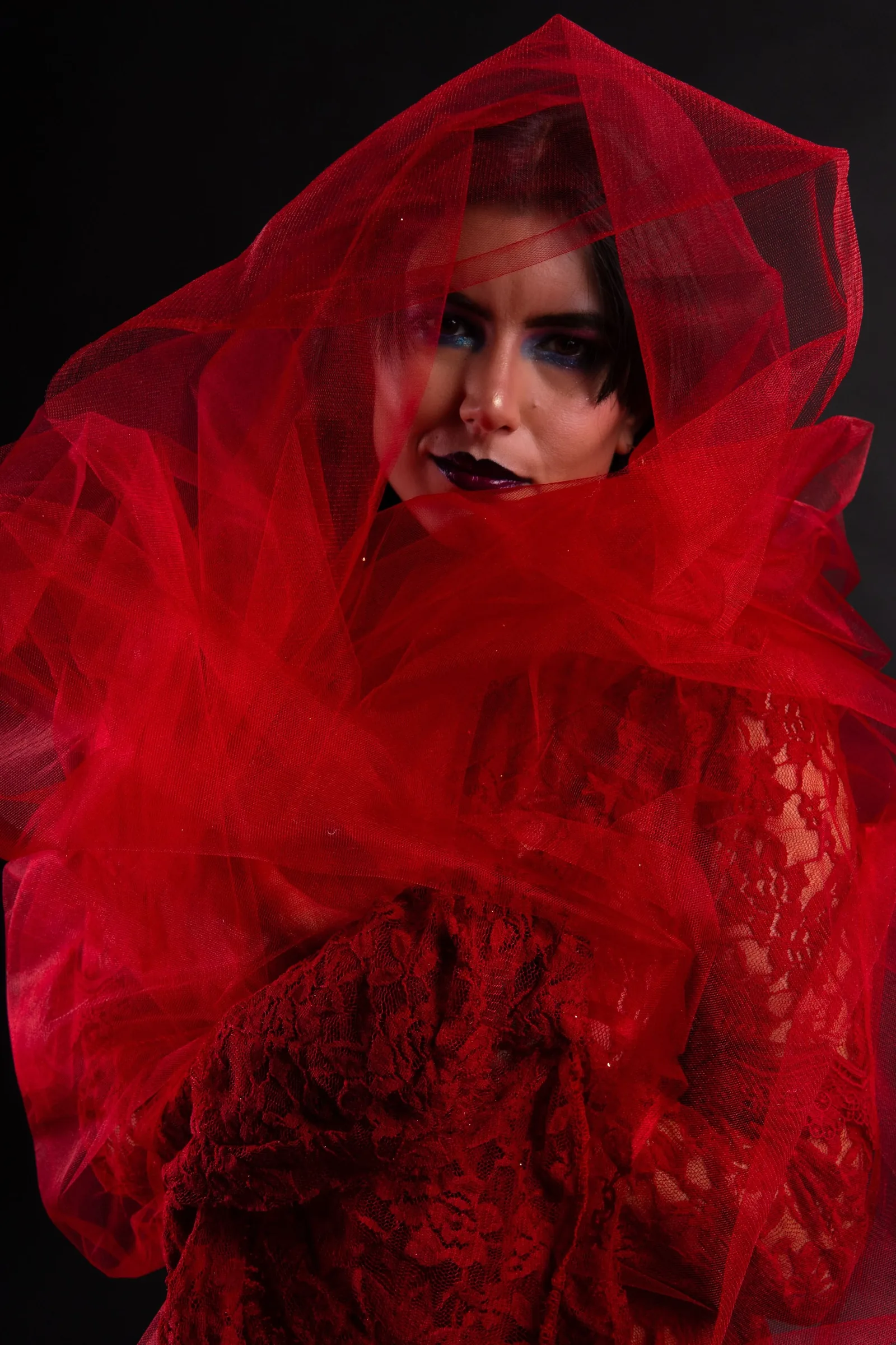 Model wrapped in red tulle against a black background