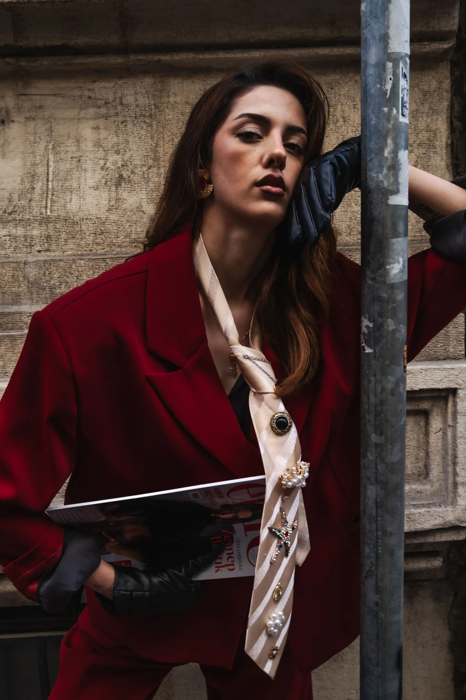 Model in a red suit leaning on a pole