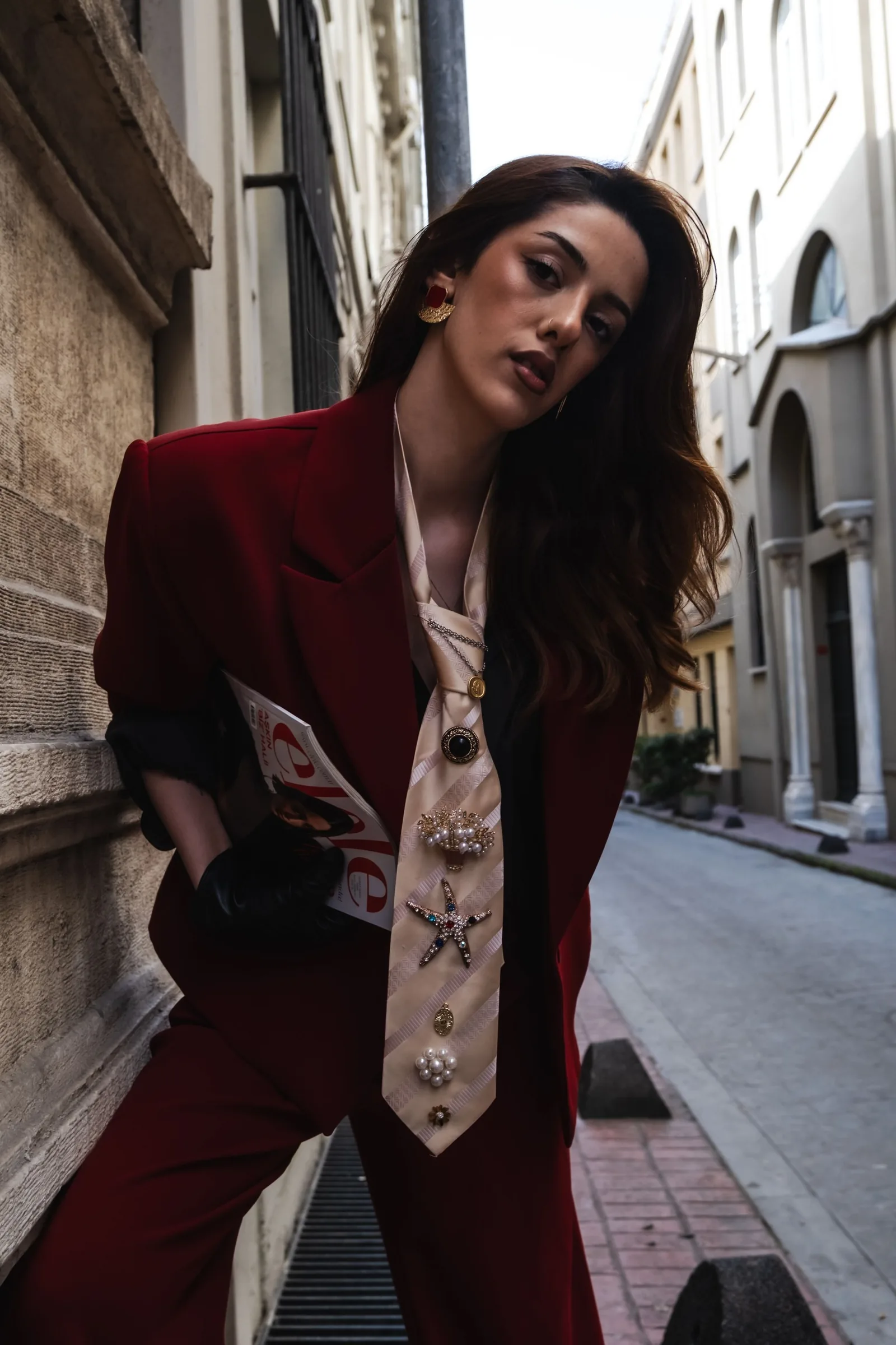 Model in a red suit walking down a narrow street